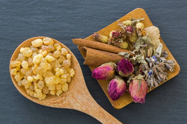 Cuchara de madera de goma aromática de resina amarilla junto a flores secas brotes de rosa canela de lavanda — Foto de Stock