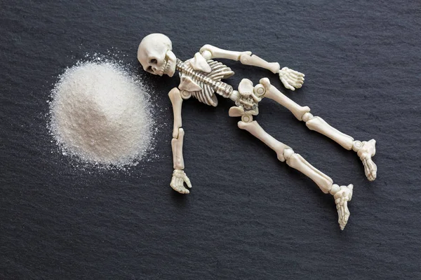 Scheletro bianco ossa del corpo morto che riposano accanto a polvere bianca pericolosa come la cocaina — Foto Stock