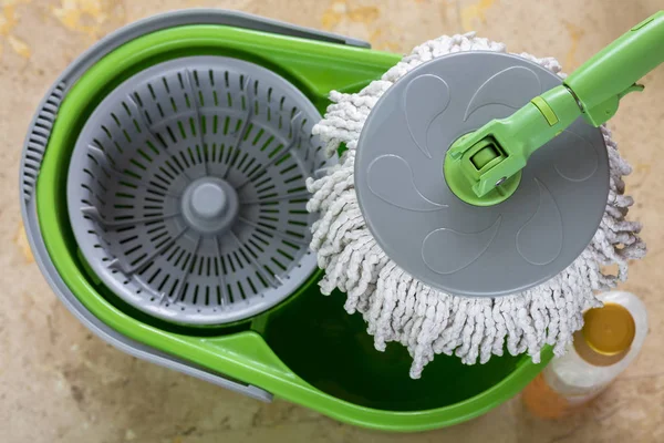 Used round spin mop with microfiber head, green handle on cleaning bucket — Stock Photo, Image