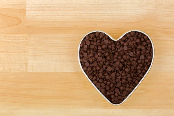 Petits morceaux de pépites de chocolat sucrées dans un bol en étain en forme de coeur — Photo