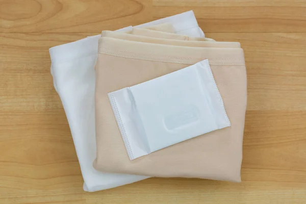 Новые неиспользованные гигиенические салфетки (гигиеническое полотенце, гигиеническая прокладка, менструальная прокладка) на белом нижнем белье — стоковое фото