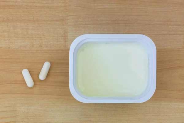Laag vet yoghurt naast witte Yoghurt capsules met culturen — Stockfoto