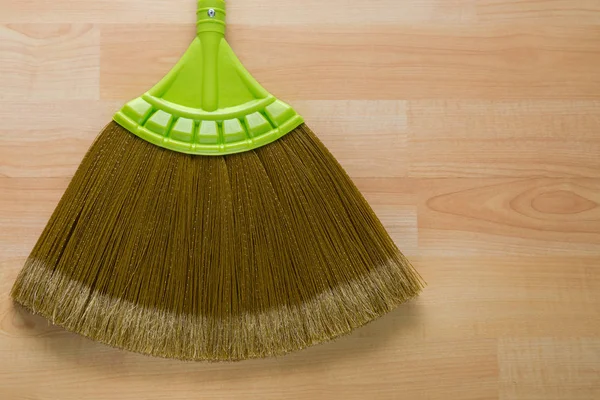 New broom made of synthetic Nylon fiber with green handle on wooden background — Stock Photo, Image