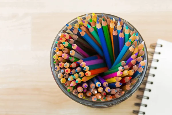 Κάτοψη του μεγάλο ποτήρι γεμάτο χρωματισμός χρωματιστά μολύβια με θολή σκίτσο σχέδιο βιβλίο — Φωτογραφία Αρχείου