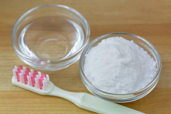 Closeup of baking soda powder next to vinegar, toothbrush on wood — Stock Photo, Image