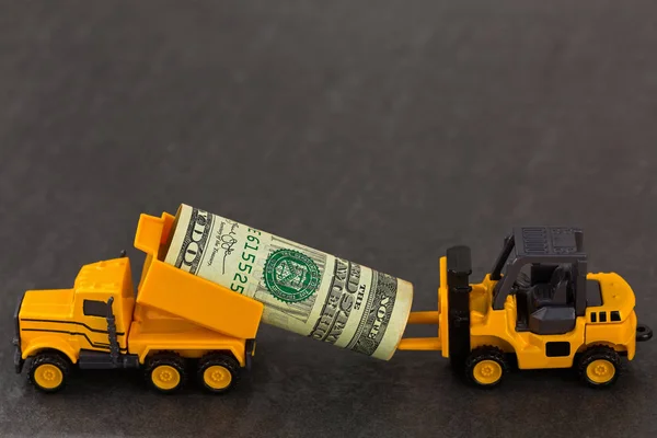 Camión volquete amarillo que lleva dinero en dólares que envía a la carretilla elevadora en b —  Fotos de Stock