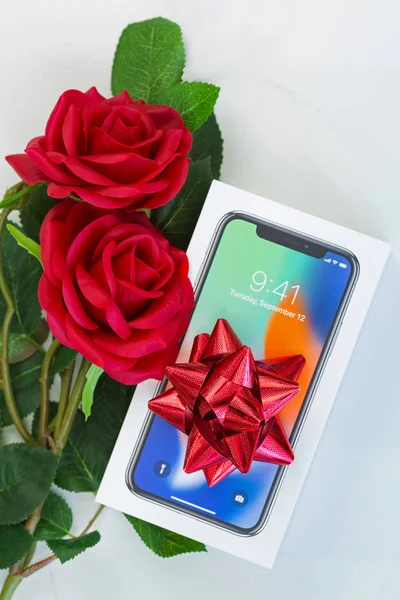 Коробка нового iPhone X (iPhone 10) с видом сверху на красную ленту и красные джинсы в подарок — стоковое фото