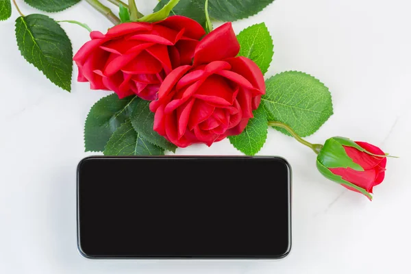 Пустой экран нового смартфона рядом с красными розами на мраморном фоне — стоковое фото