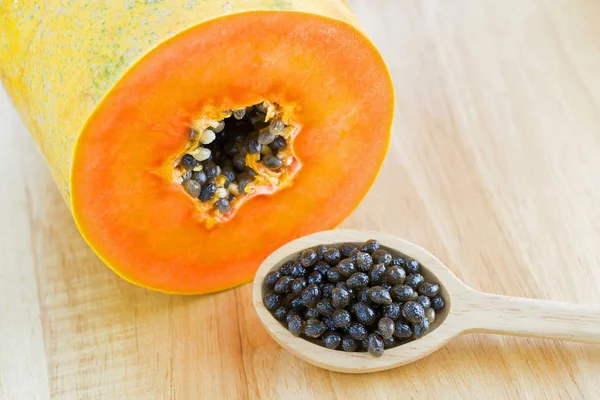 Semillas de papaya fresca junto a fruta de papaya cortada que muestra textura naranja — Foto de Stock