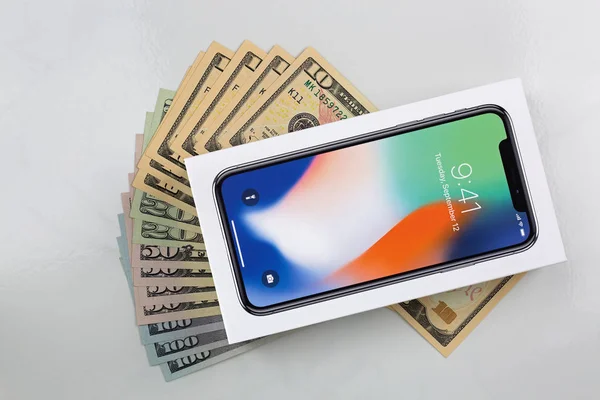 Ящик нового iPhone X (iPhone 10) на американских банкнотах на мраморном фоне — стоковое фото