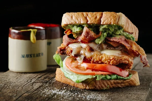 Koyu arka planda kızarmış tavuk ve avokado ile BLT sandviç
