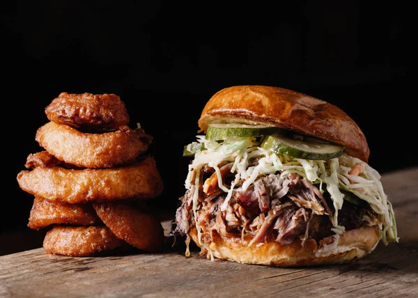 Pulled Pork Sandwich with Onion Rings on rustic background — Stock Photo, Image