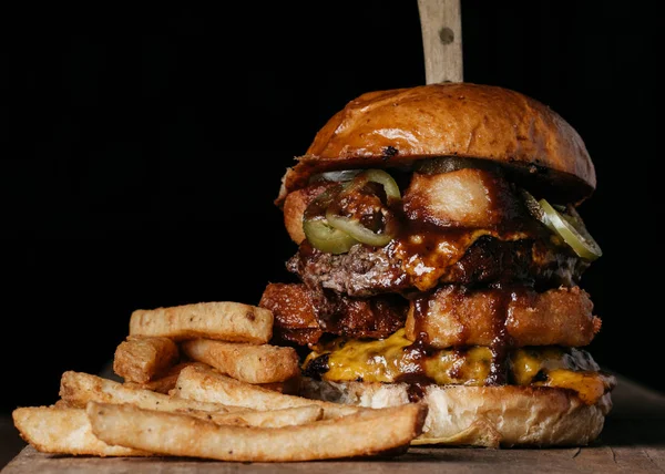 Köy arka planında patates kızartması olan lezzetli bir hamburger. — Stok fotoğraf