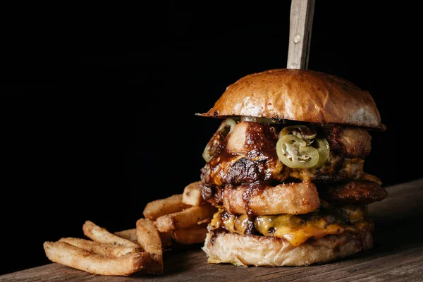 Koyu arkaplanda patates kızartması olan Sulu Dev Burger.