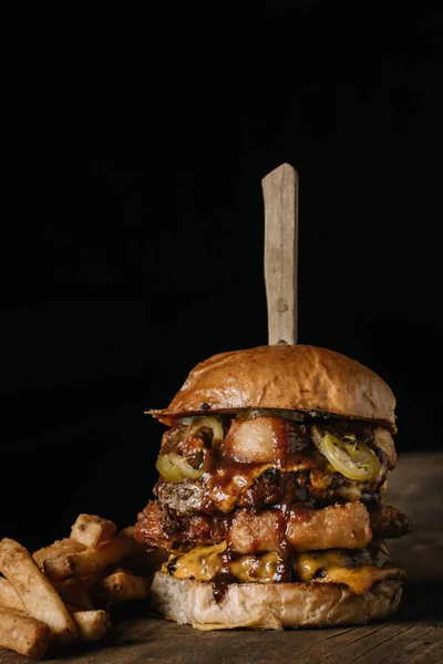 Burger dublu stivuit cu cartofi prăjiți pe fundal întunecat — Fotografie, imagine de stoc