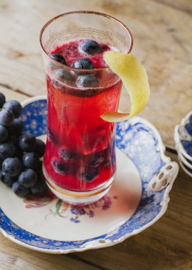 Cranberry color cocktail  garnished with fresh grapes on a vinta