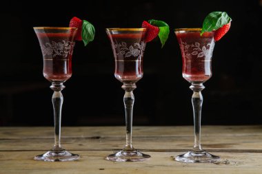 Three strawberry and basil cocktails in vintage glasses
