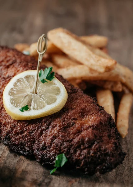 Fried catfish served with french fries on rustic background