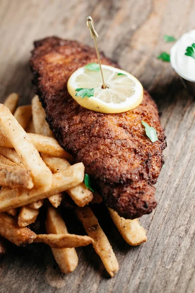 Pesce gatto fritto servito con patatine fritte su sfondo rustico — Foto Stock