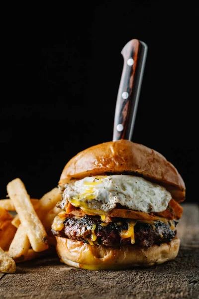 Hamburger da colazione con uovo fritto su superficie rustica scura — Foto Stock