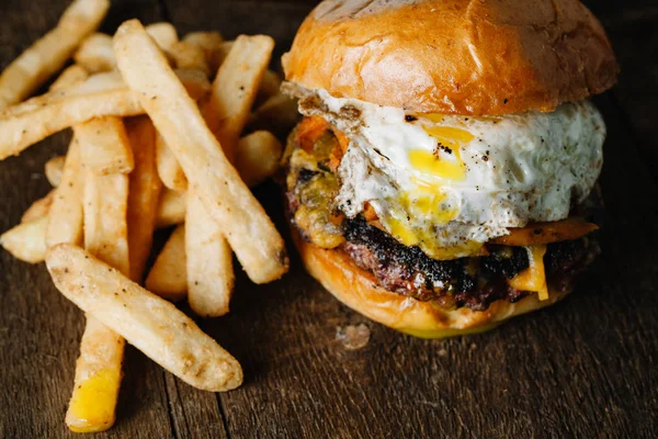 Breakfast burger with a fried egg on dark rustic surface