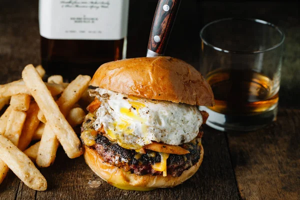 Hamburguesa de desayuno con un huevo frito en la superficie rústica oscura — Foto de Stock