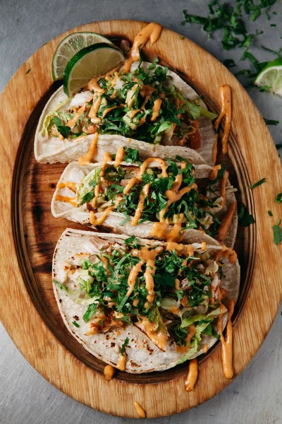 Três tacos de peixe com alface, tomate, abacate em um prato de madeira — Fotografia de Stock