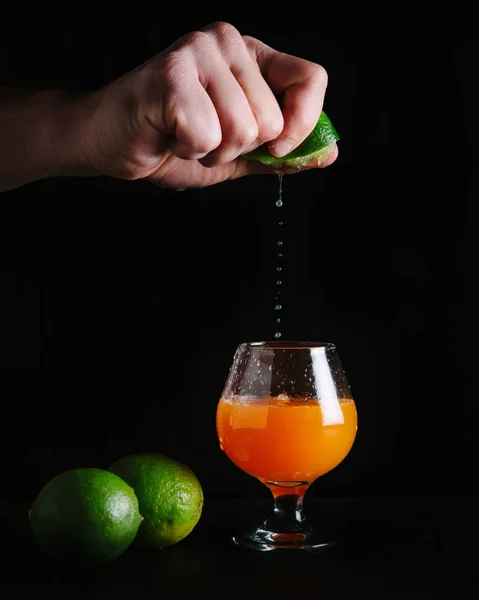 Bartender squeezing a lime into an alcoholic cocktail — ストック写真