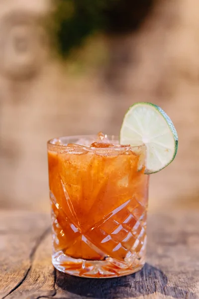An colorful alcoholic cocktail garnished with a slice of lime — Stock Photo, Image