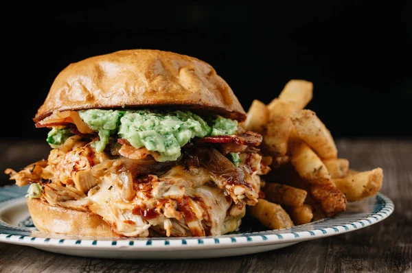 Koyu arkaplanda patates kızartmalı tavuk burger.
