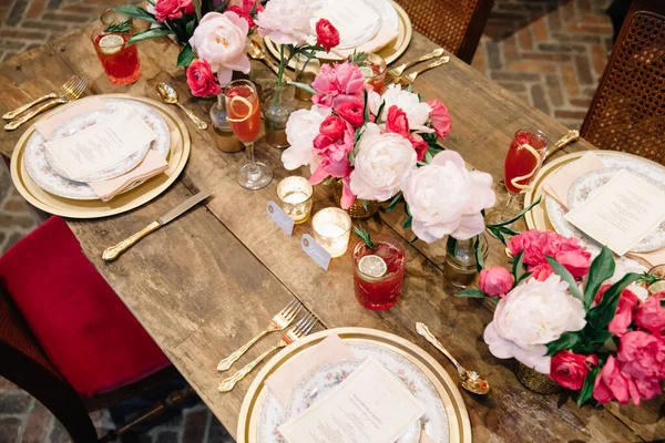 Elegant dark pink wedding banquet table with glasses, dishes and flowers decoration indoors in restaurant. Gorgeous long wedding table. Wedding decoration concept. Magenta color
