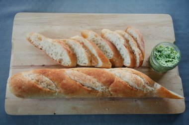 İtalyan beyaz ekmeği dilimlenmiş ve ahşap bir yüzeyde ev yapımı dereotu yağı ile servis edilmiş.