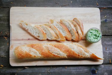 İtalyan beyaz ekmeği dilimlenmiş ve ahşap bir yüzeyde ev yapımı dereotu yağı ile servis edilmiş.