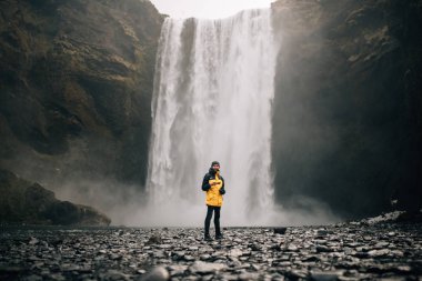 Bir ölçek olarak ayakta erkeklerin gökkuşağı ve silueti ile Skogafoss şelale, İzlanda