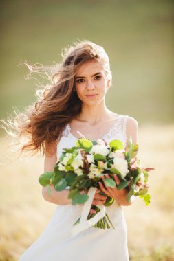 gelinlik gelin, doğada elinde buket ile