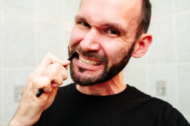 Traş köpüğü ve havluyla jilete homurdanan bir adam.