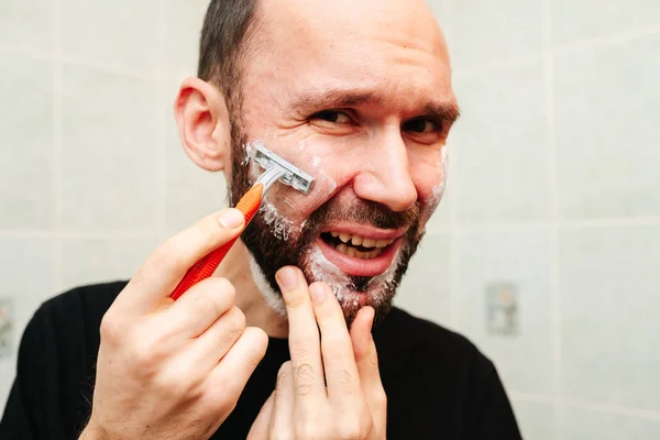 Homme grognant au rasoir avec de la crème à raser et une serviette — Photo
