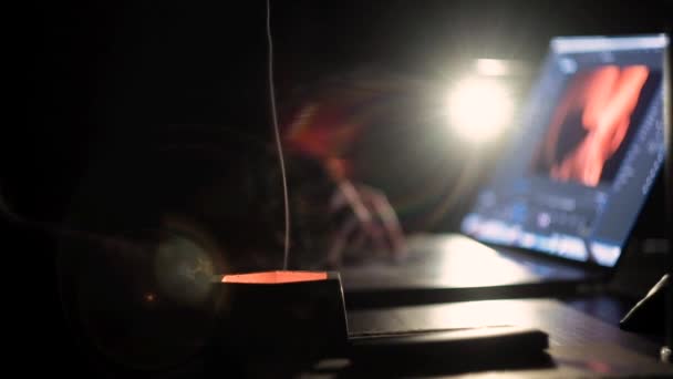 Mężczyzna ręce wpisując na klawiaturze laptopa w ciemności przy świetle lampy — Wideo stockowe