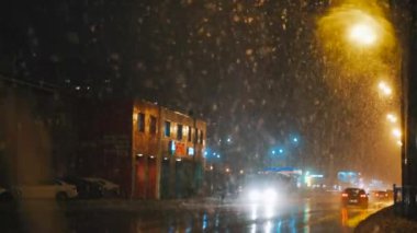 snowfall on the street against the background of passing cars