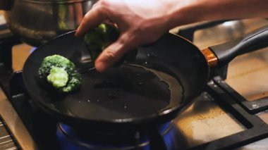 Adam brokoli yeşil fasulyelerini kızgın tavada karıştırıyor.
