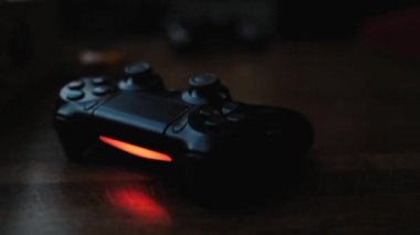 Video game controller on a wooden table in a dark room with red backlight