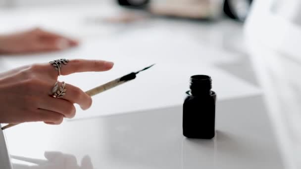 Frau hält Stift für Kalligraphie in der Hand und weicht in Tintenfass ein — Stockvideo