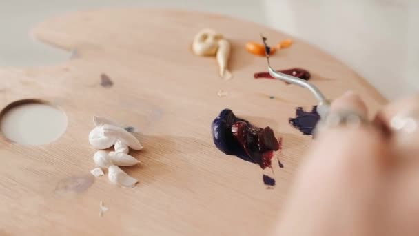 Женщина смешивает масляные краски на деревянной палитре . — стоковое видео
