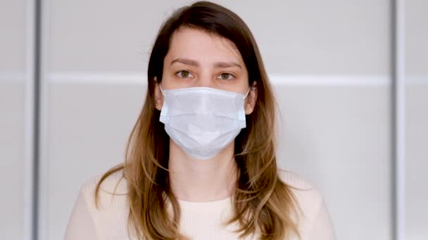 Close-up van een jonge vrouw met een beschermend medisch masker — Stockvideo