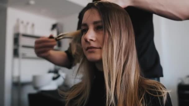 Крупный план парикмахера расчесывания волос клиентов, юная кавказская девушка — стоковое видео