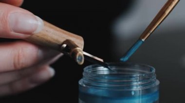 girl soaks a calligraphy pen in blue mascara