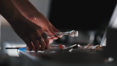 girl collects drawing tools on the table. Paints, tubes, brushes.