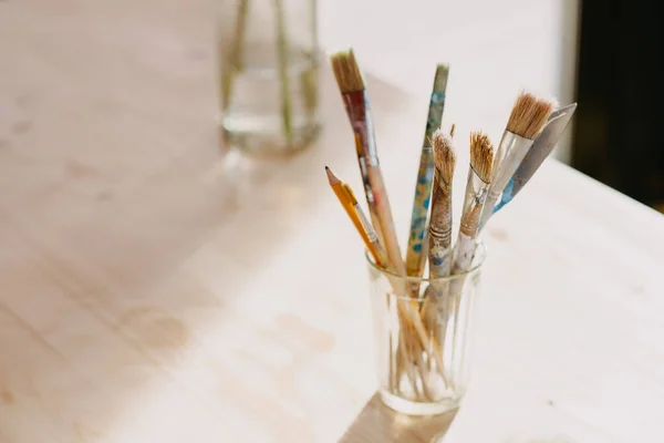  A brush in a glass on a light background backlit by the rays of the sun. 