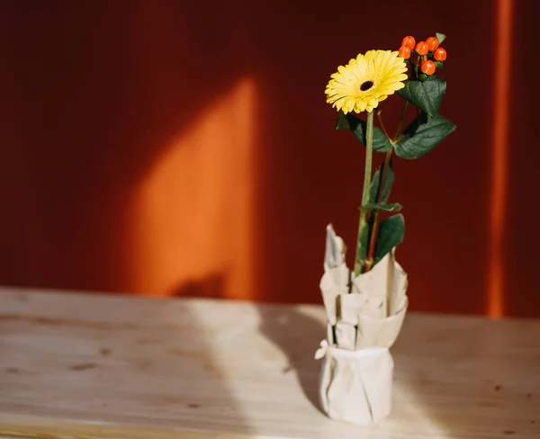 Flor amarilla de gerberas en un jarrón artesanal sobre una mesa retroiluminada por el sol — Foto de Stock