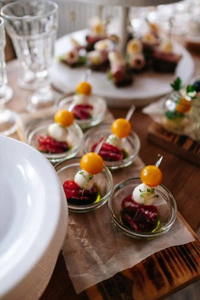 Glasses with seafood snacks and meat on banquet table